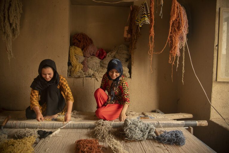 Weavers working on a traditional loom in their house in Aqcha district in northern Afghanistan